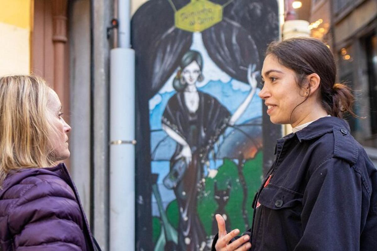 due donne in piedi una accanto all'altra davanti a un murale