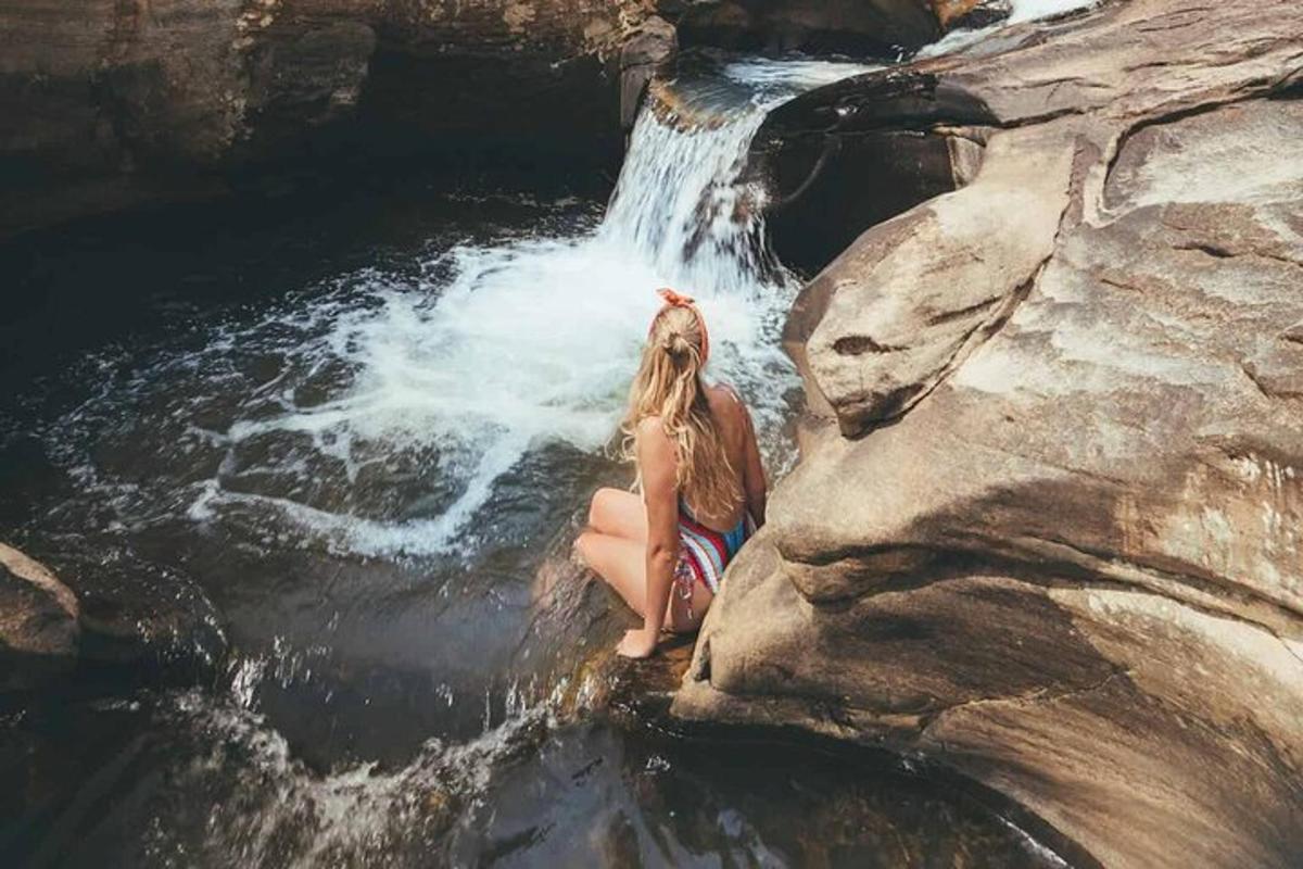una donna seduta su una roccia accanto a una cascata