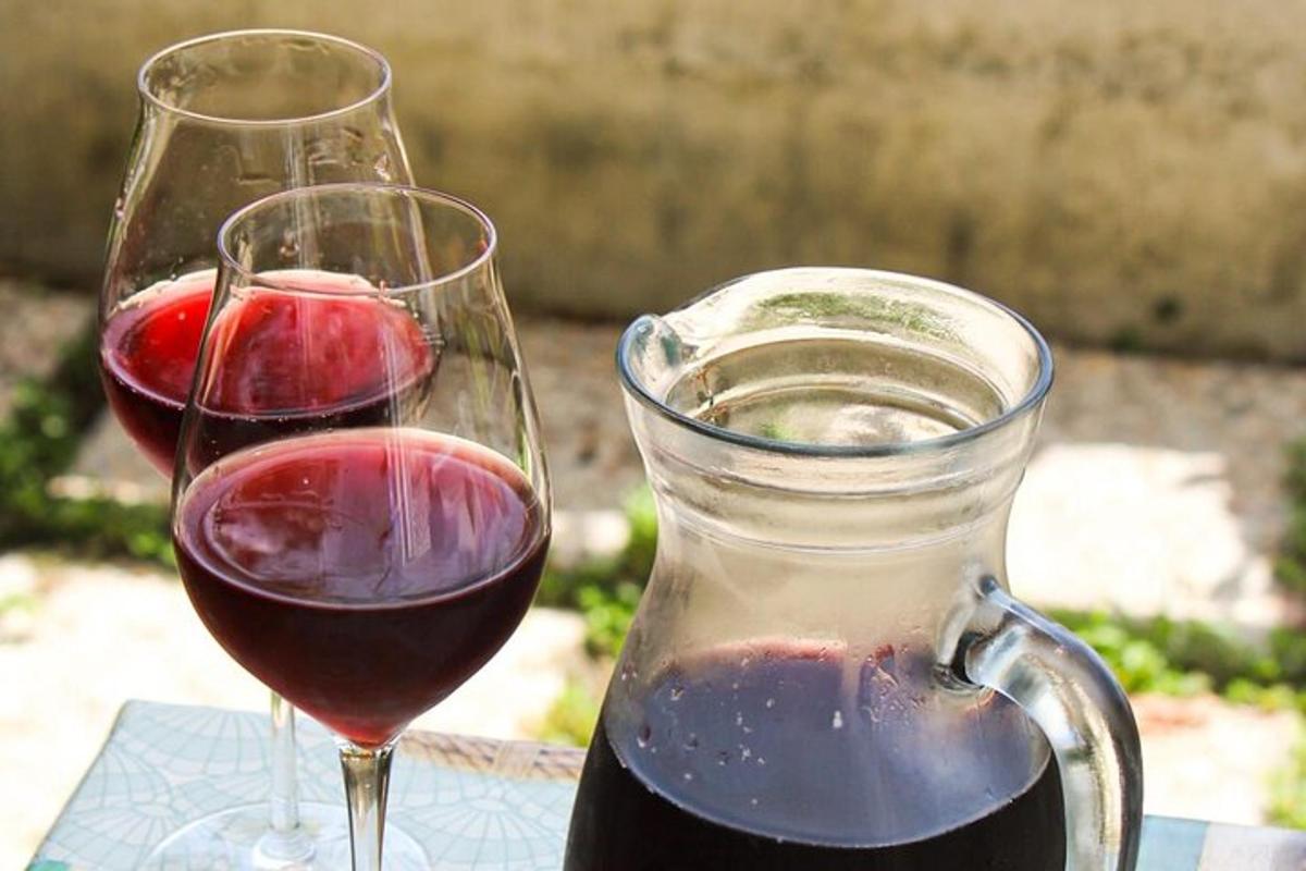 dvije čaše crnog vina pored vrča vina
