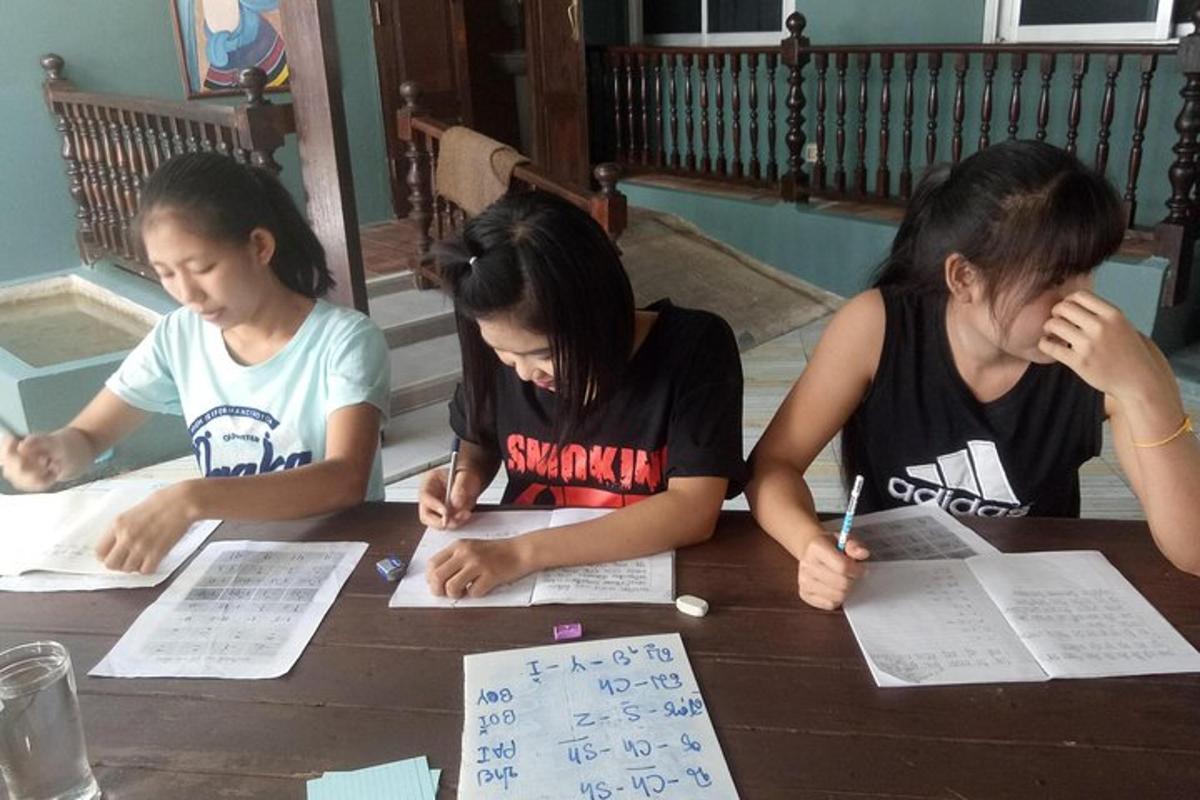 ba cô gái đang ngồi ở bàn viết trên giấy
