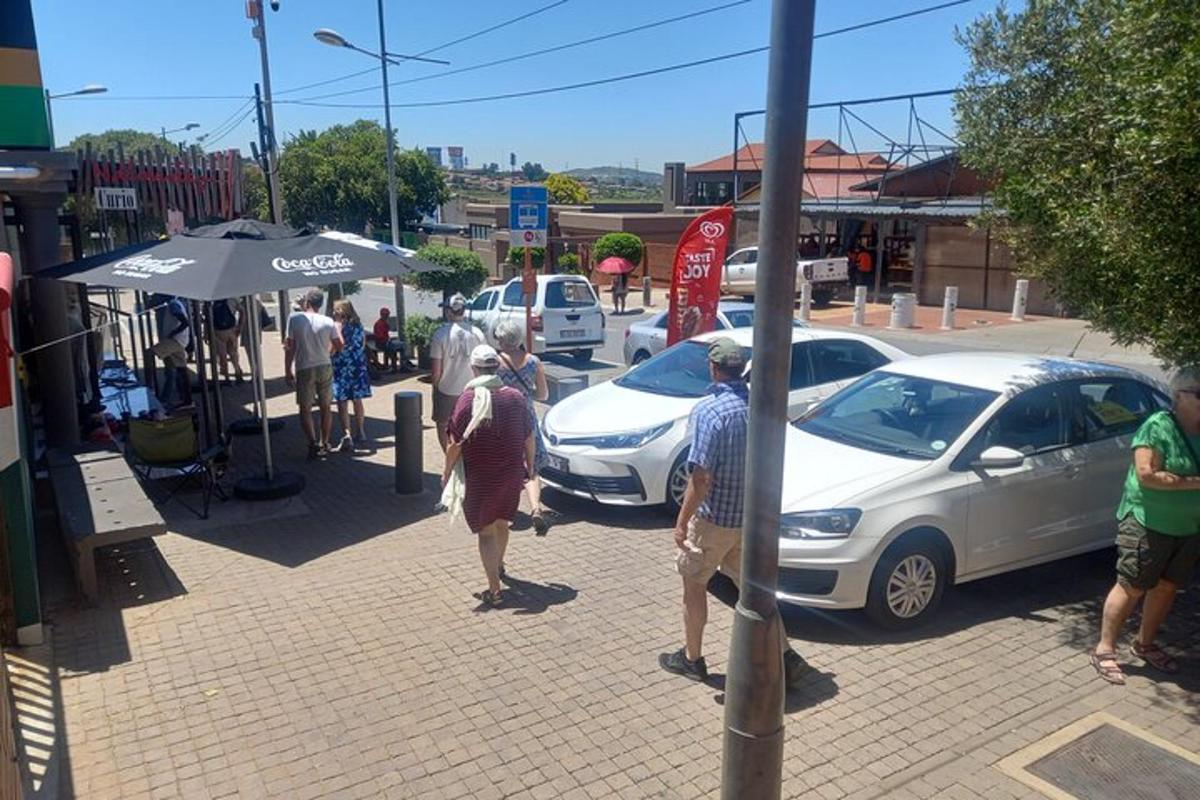 um grupo de pessoas em pé na calçada perto de carros