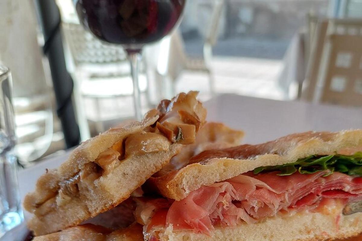 a sandwich cut in half on a plate with a glass of wine