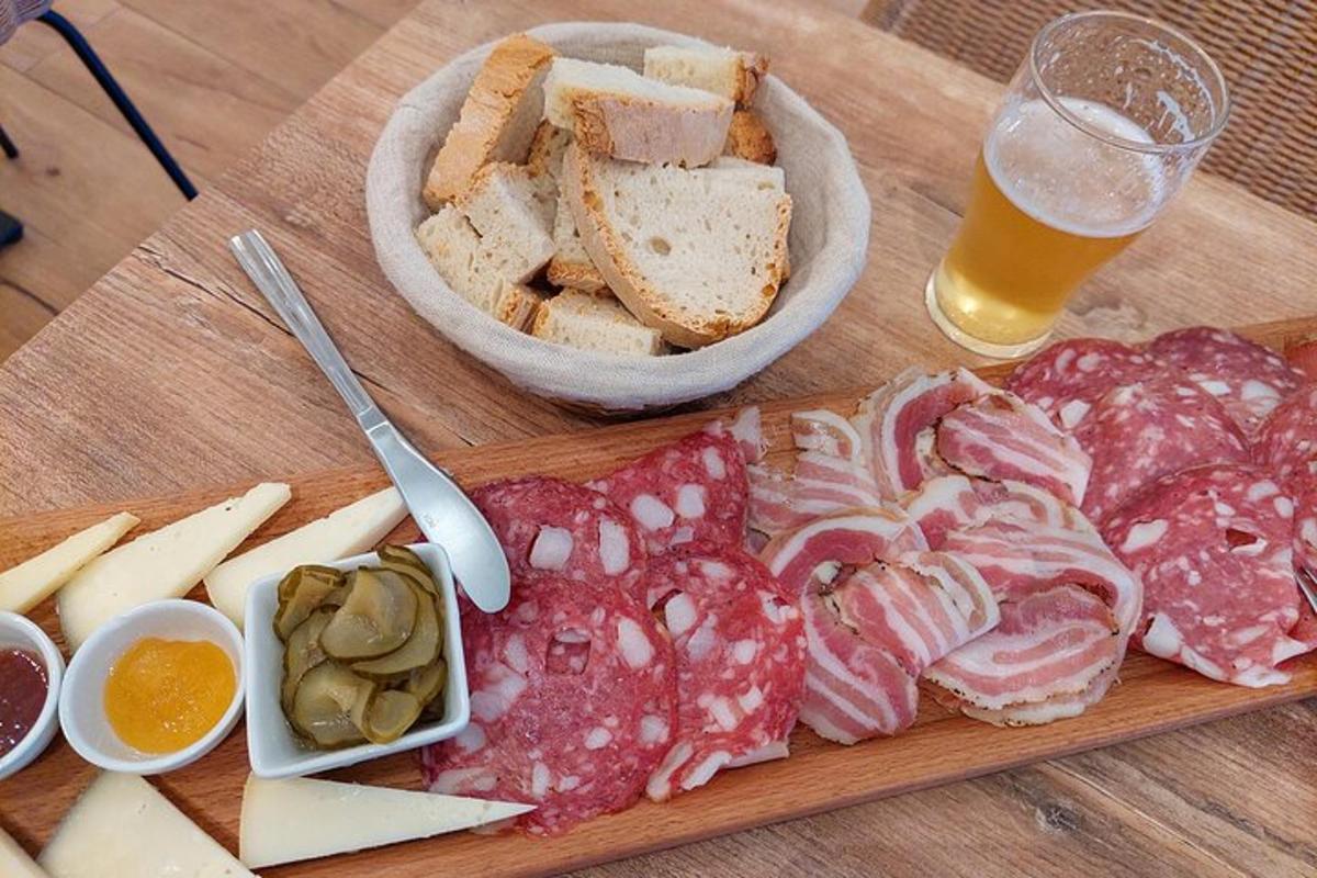 un tagliere con carne e pane e un bicchiere di birra
