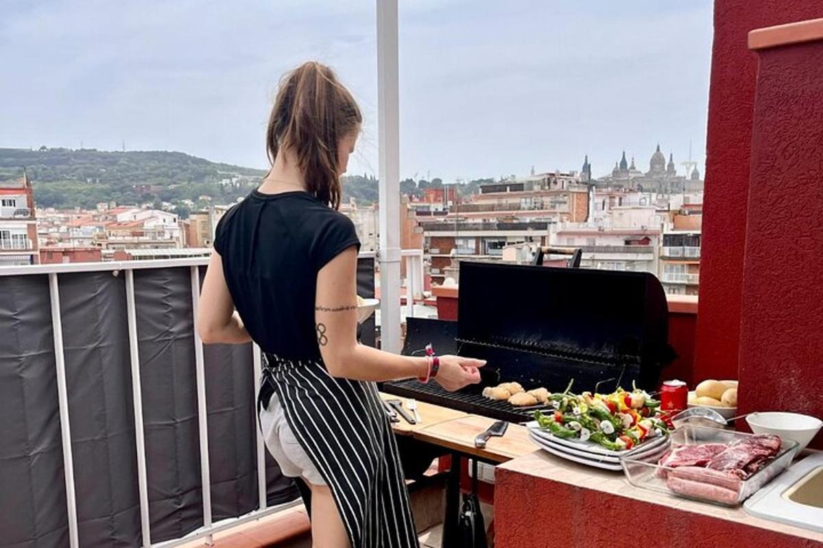 žena stojící na balkóně a vařící jídlo na grilu