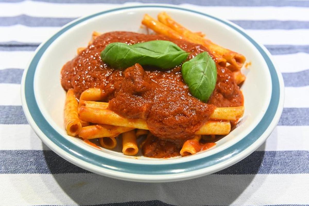 en skål pasta med sauce og basilikum på et bord