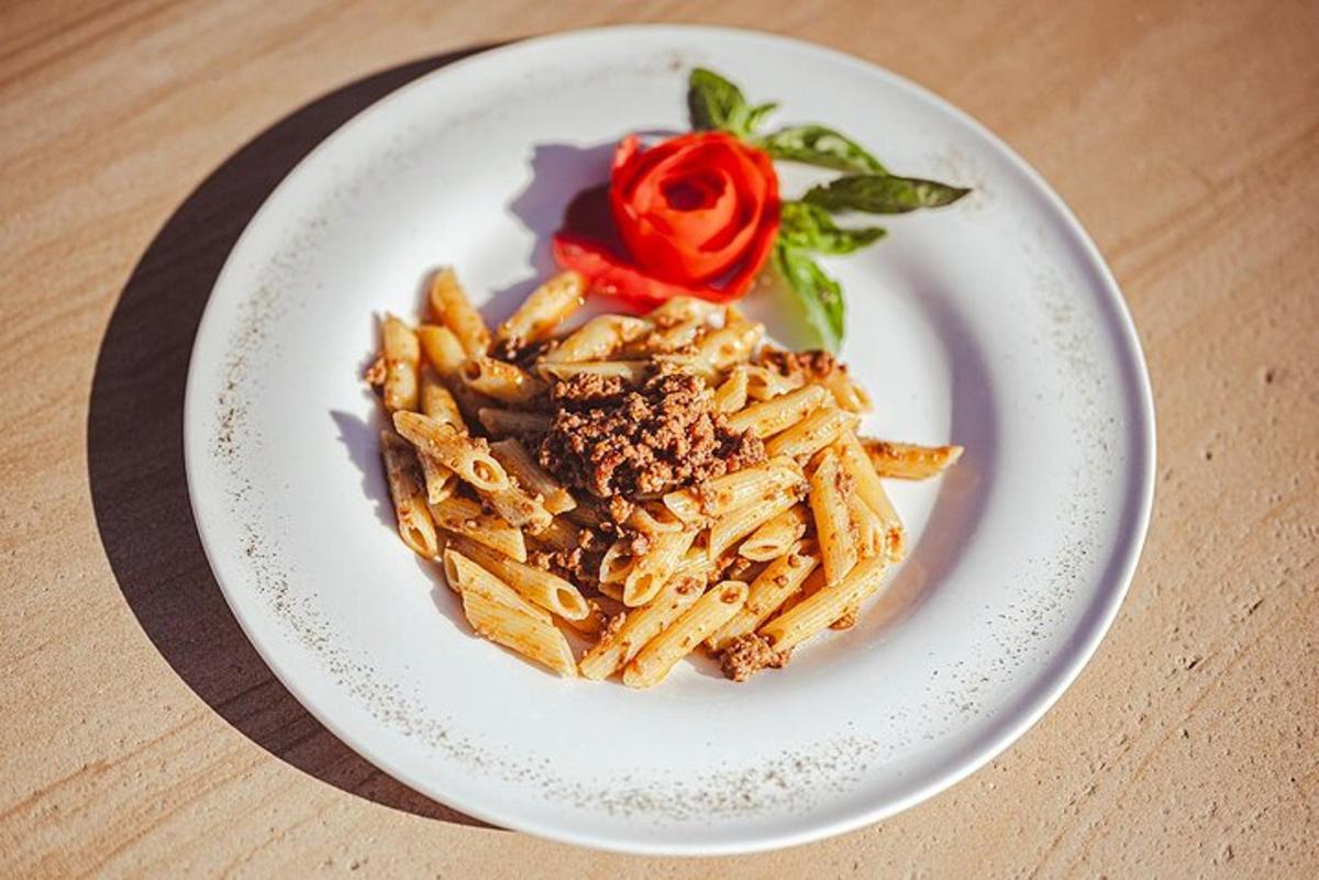 sepinggan pasta dengan mawar merah di atas meja
