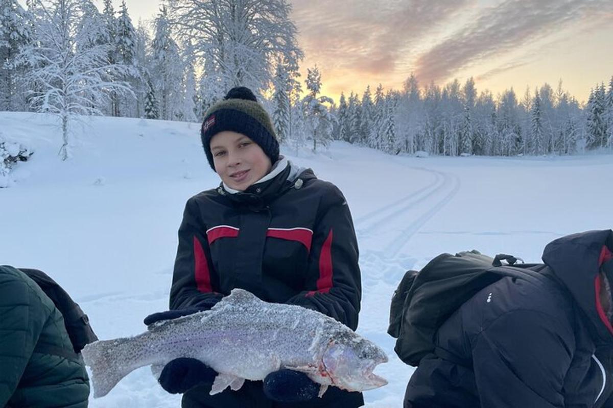 a boy holding a fish in the snow