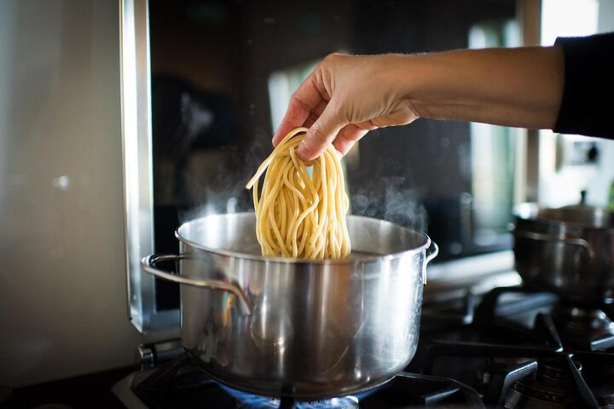 ストーブの上の鍋に麺を持っている人