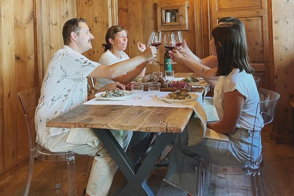 skupina ljudi, ki sedijo okoli mize in pijejo vino