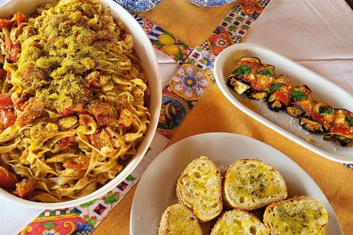 pöytä, jolla on kaksi kulhoa pastaa ja lautanen leipää