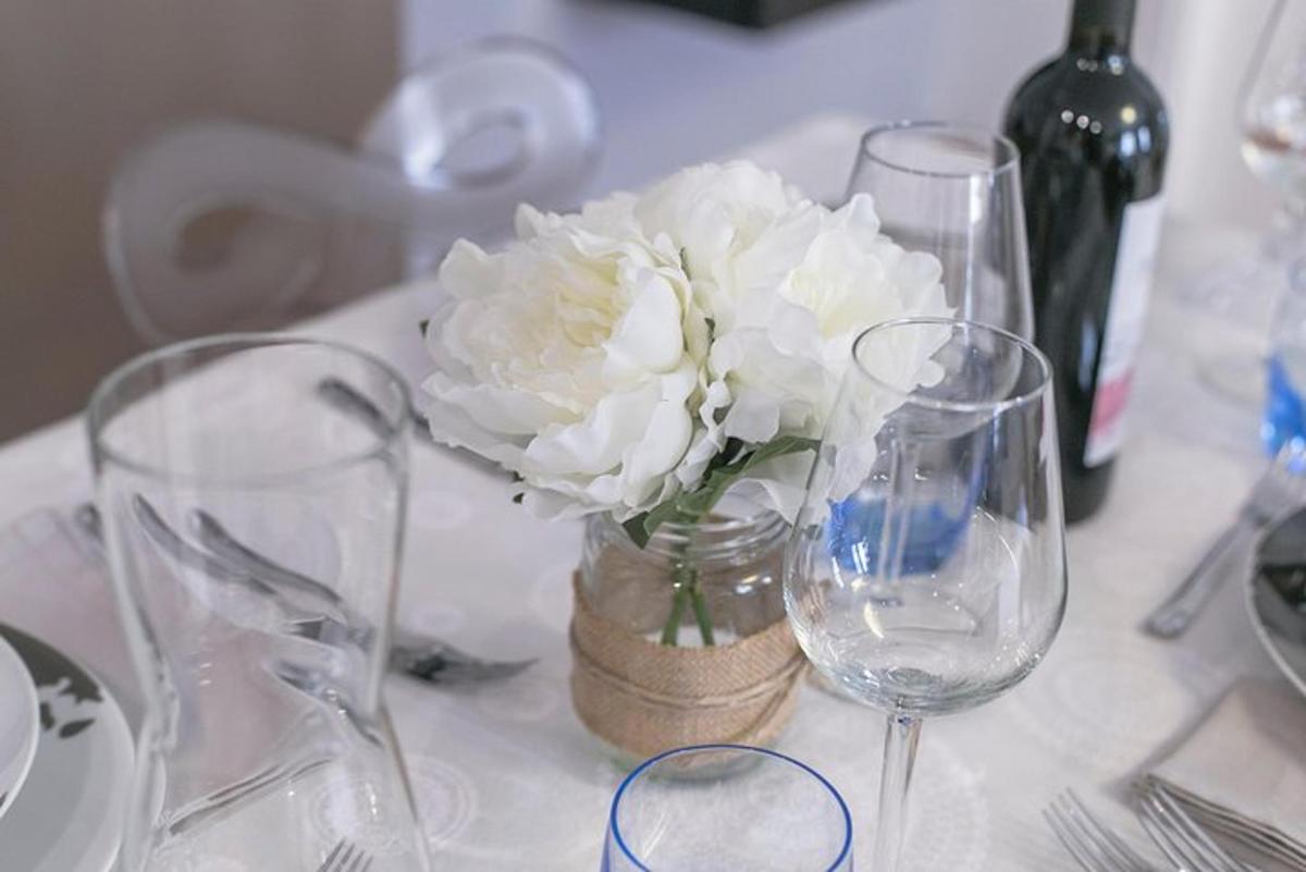 un tavolo con bicchieri e un vaso con fiori bianchi