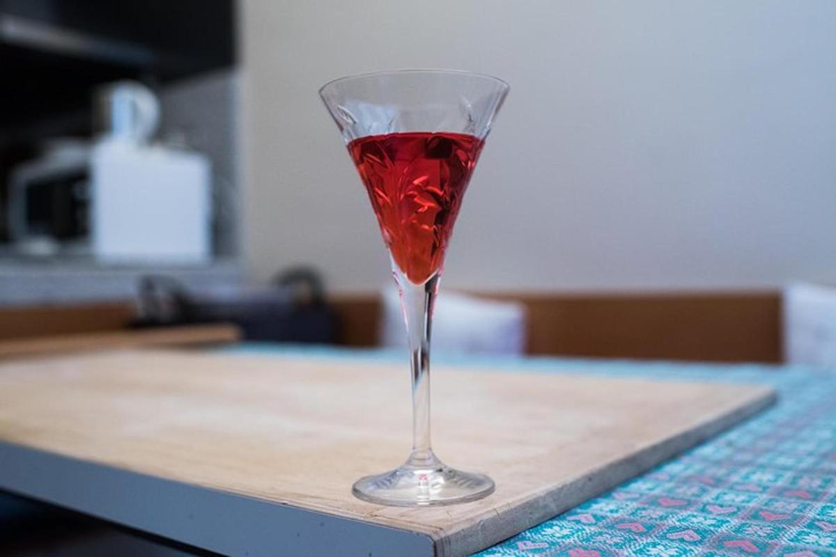 a red drink in a wine glass sitting on a table