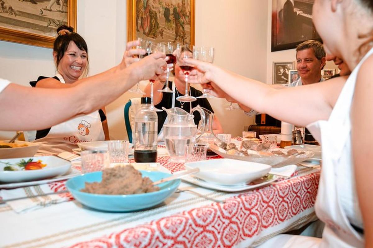 skupina lidí sedících kolem stolu a popíjejících víno