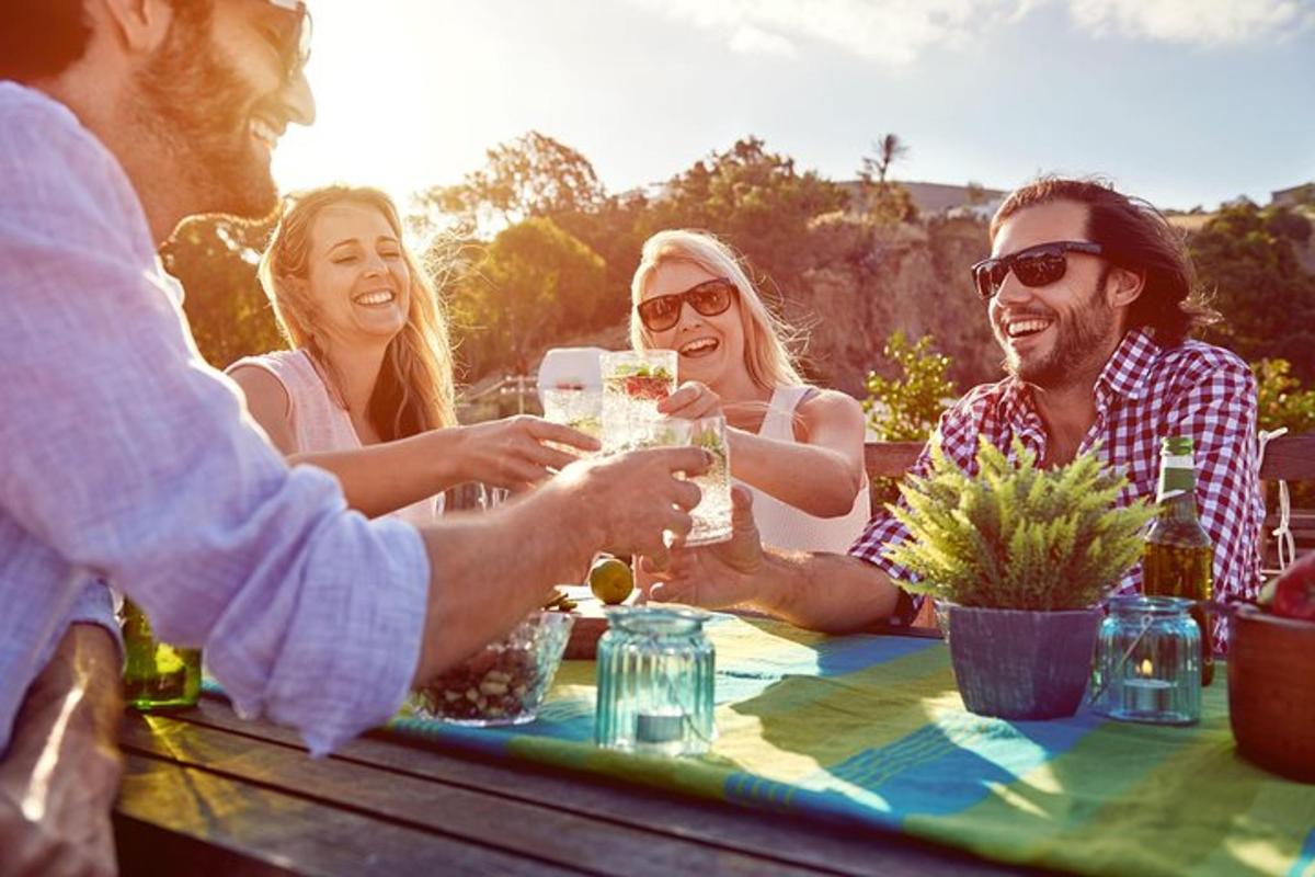 grupp inimesi istub laua ümber ja joob veini
