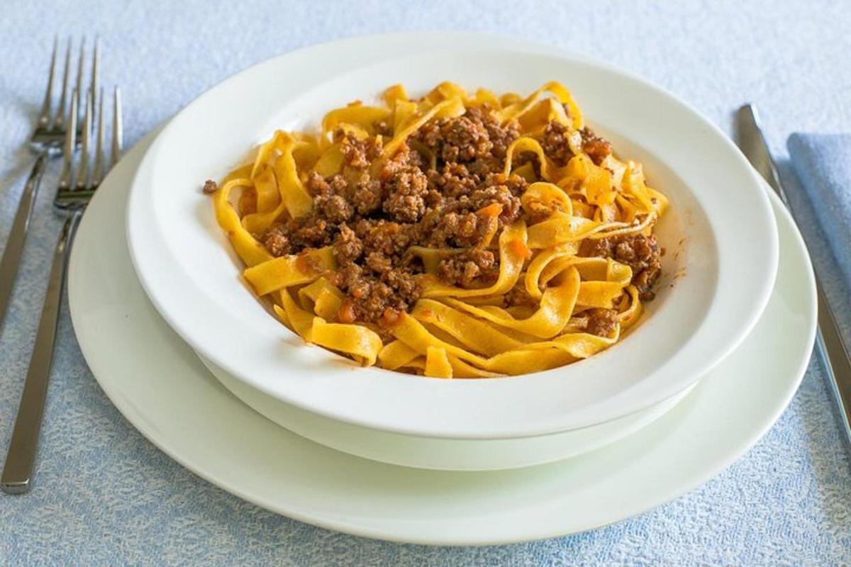 Un tazón de pasta con carne en un plato blanco