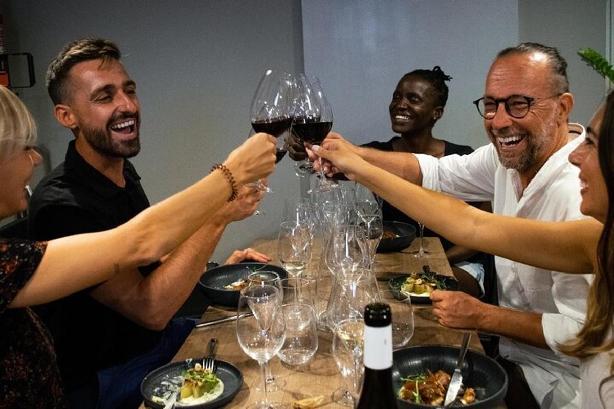 skupina ljudi, ki sedijo okoli mize in pijejo vino