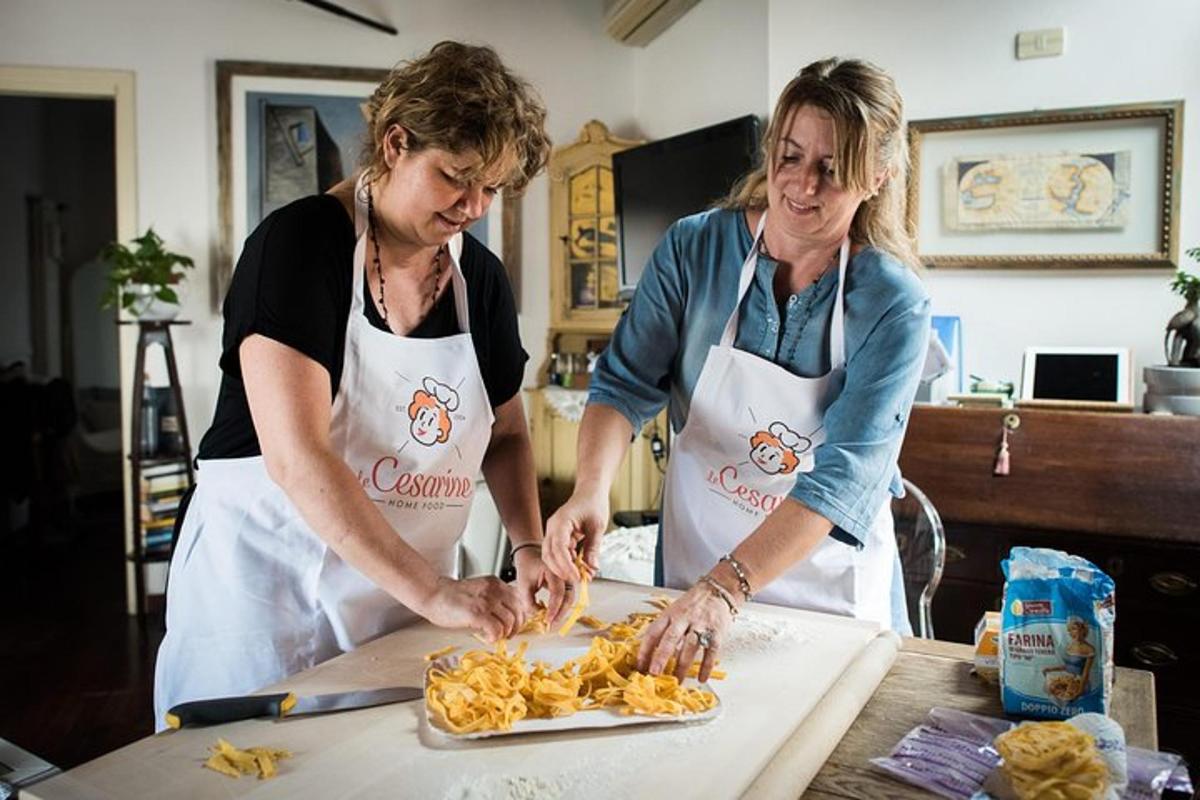 duas mulheres em uma cozinha preparando comida em uma mesa