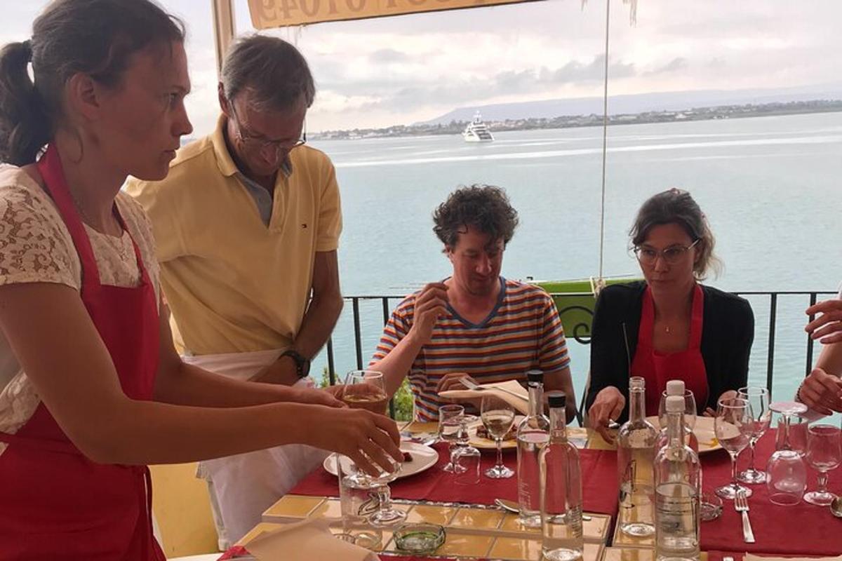 un gruppo di persone sedute a un tavolo con bicchieri di vino