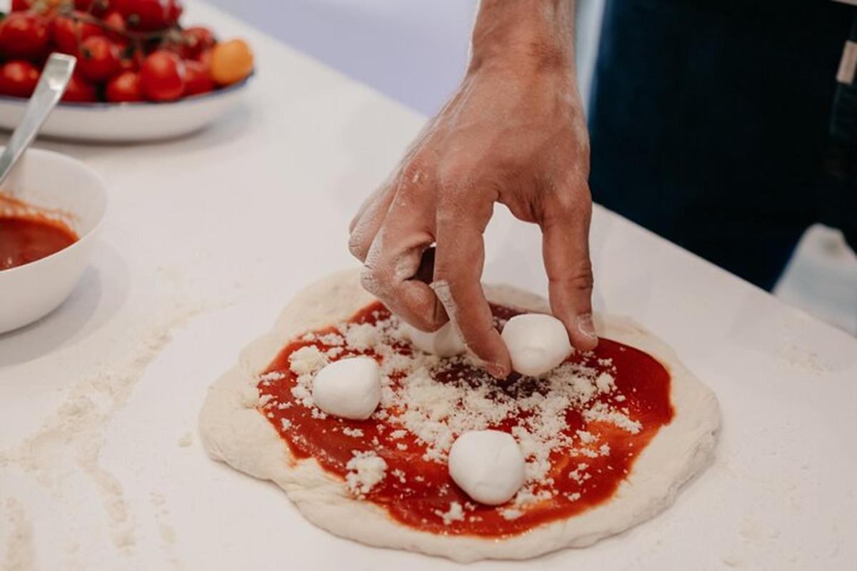 uma pessoa está fazendo uma pizza com molho vermelho e cobertura branca