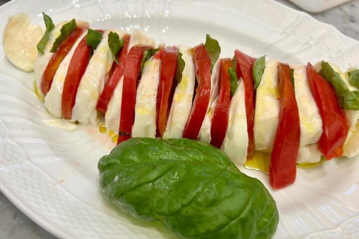 un plat blanc amb un hot dog amb bacó i enciam