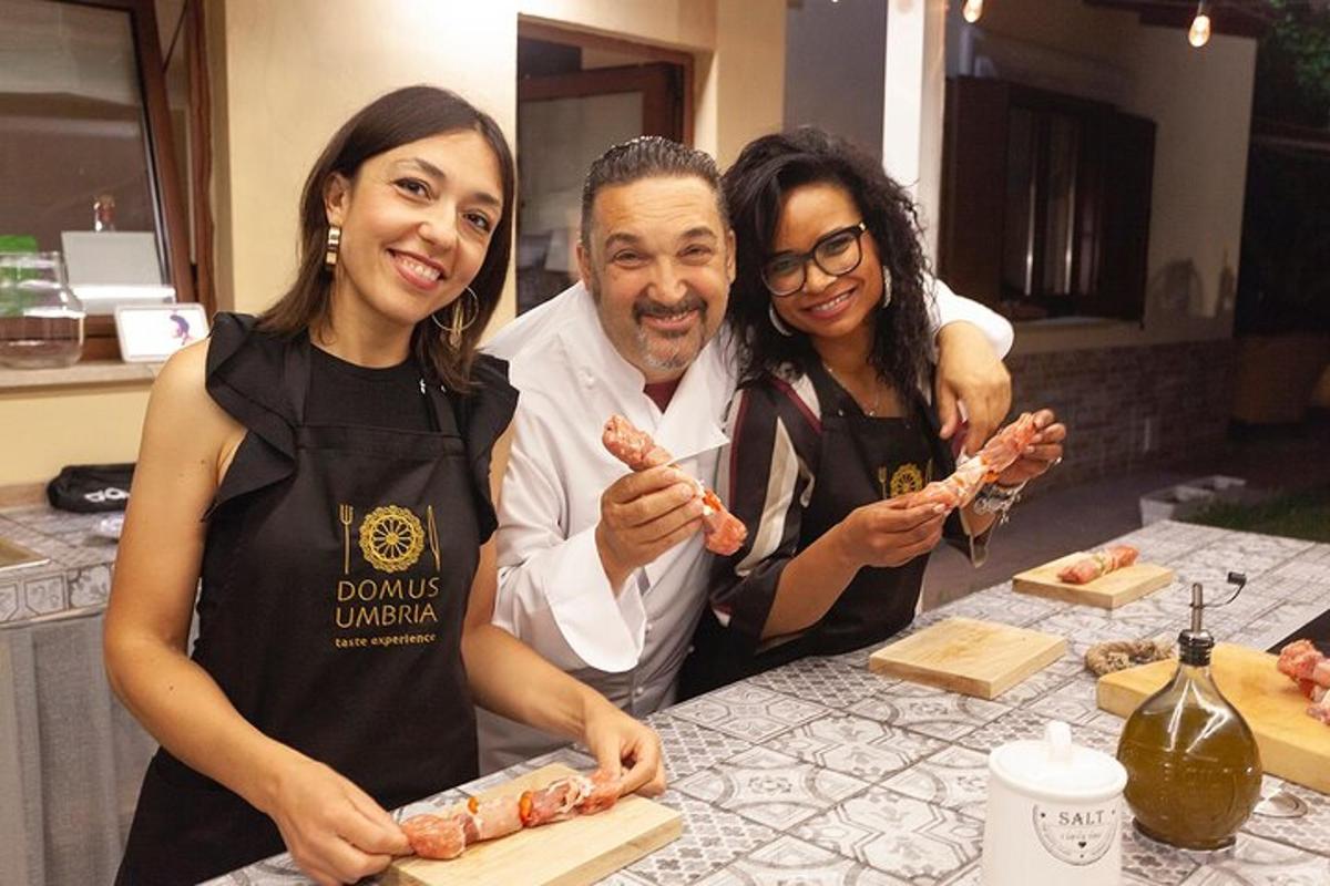 Un hombre y dos mujeres de pie en una cocina preparando comida.