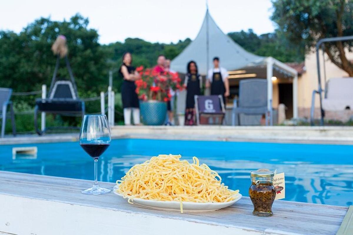 un plat de pasta i una copa de vi al costat d'una piscina