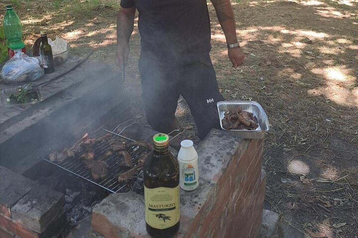 Ένας άντρας που στέκεται πάνω από μια σχάρα με ένα μπουκάλι αλκοόλ