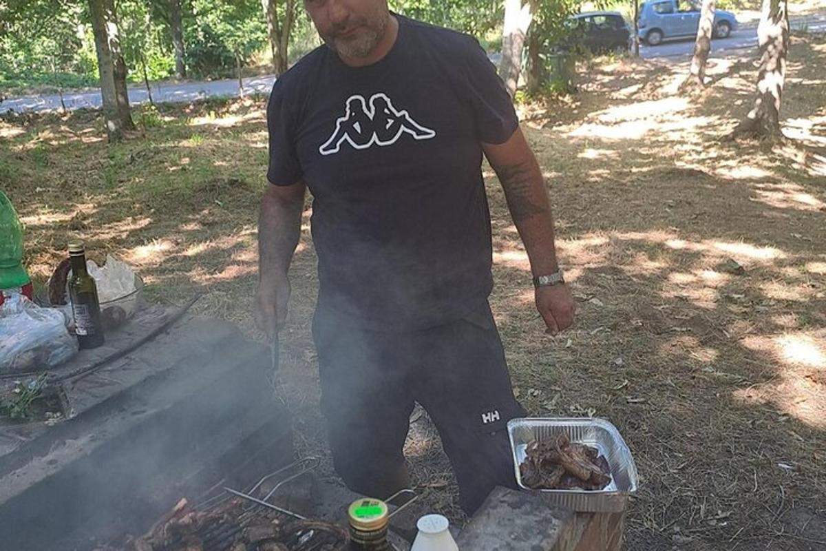 Ένας άντρας που στέκεται πάνω από μια σχάρα με ένα τηγάνι γεμάτο φαγητό
