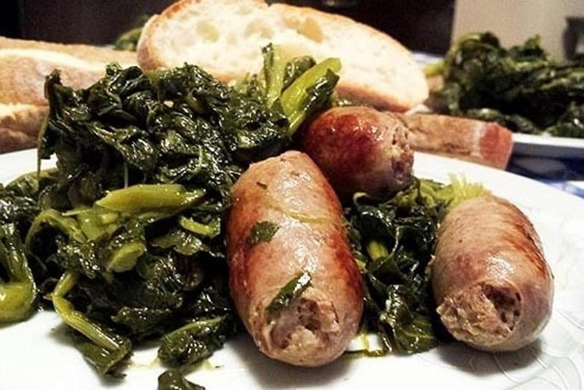 ένα άσπρο πιάτο φαγητού με λουκάνικα και χόρτα
