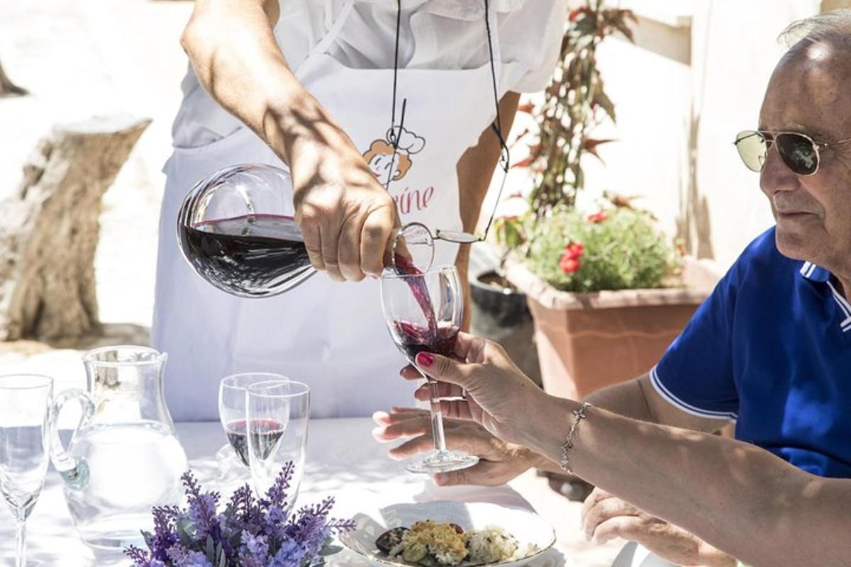 uma mulher mais velha servindo uma taça de vinho tinto