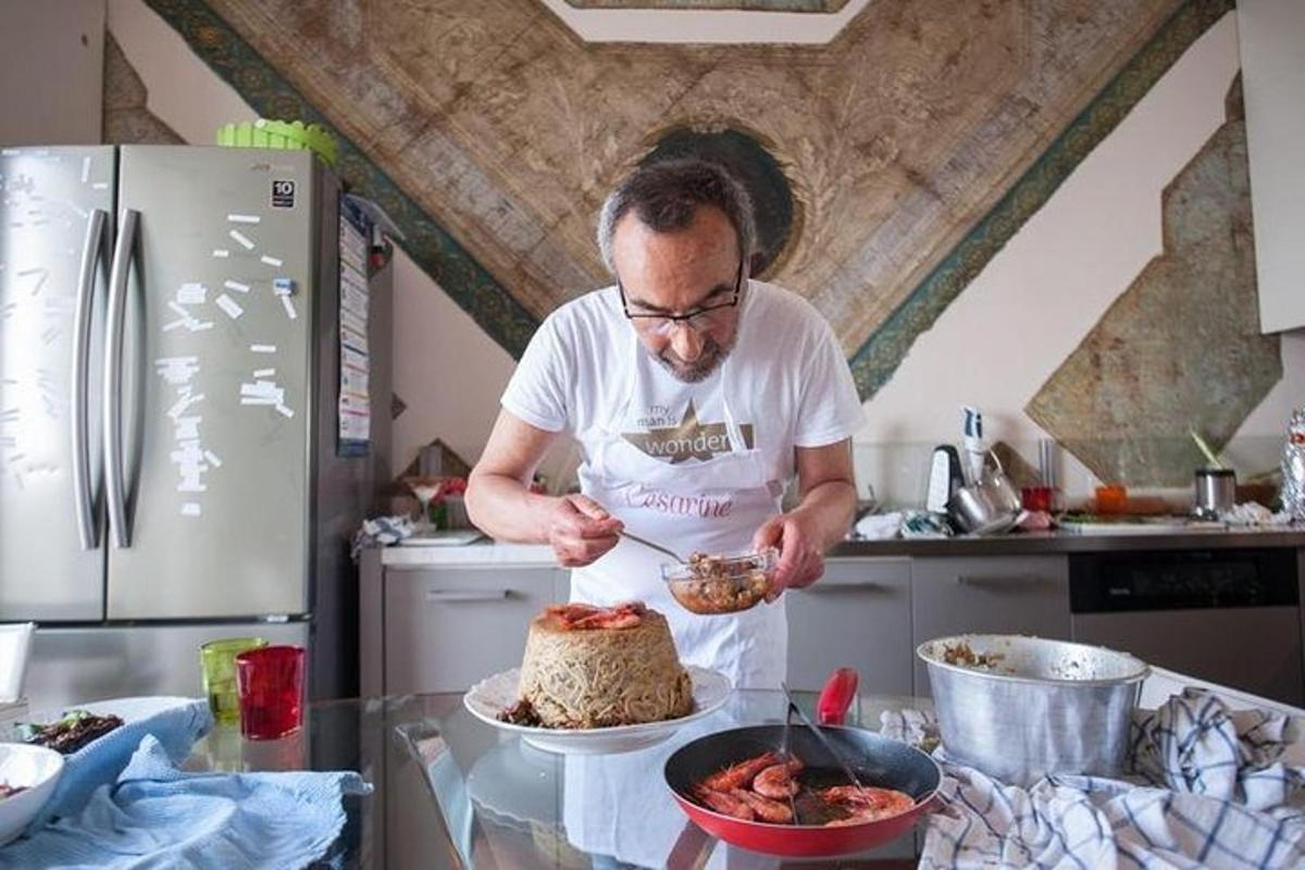 muž stojící v kuchyni a krájející dort