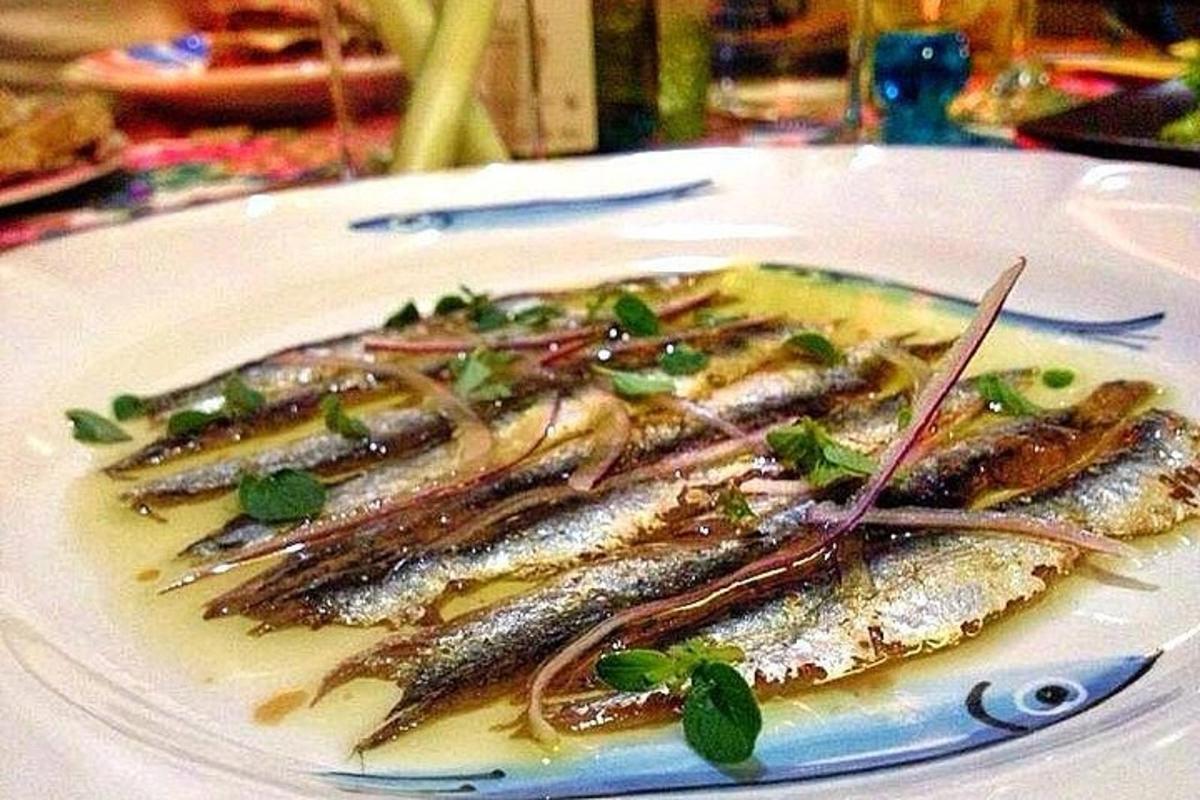 isang plato ng isda na may sarsa at mga gulay sa ibabaw nito
