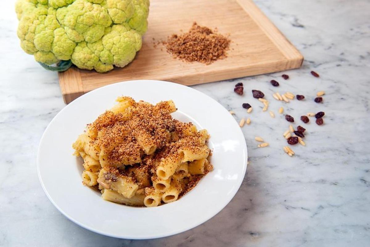 Un tazón de pasta en un plato junto a una tabla de cortar