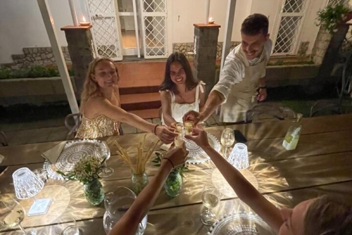 skupina lidí sedících kolem stolu s vinnými sklenicemi