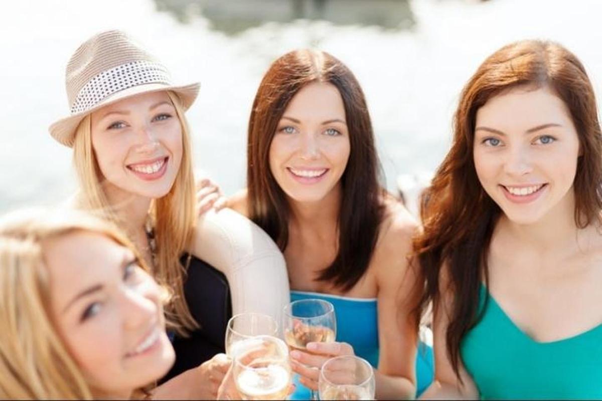 Un grupo de mujeres sentadas en una mesa con copas de vino.
