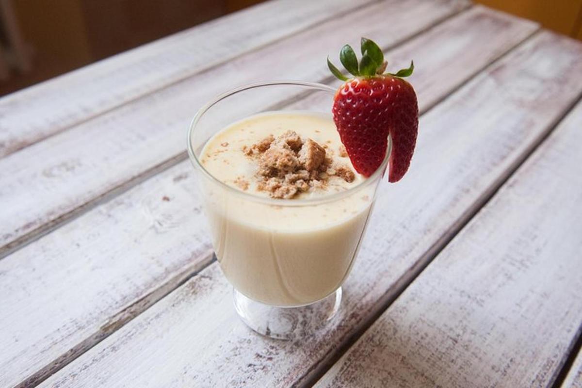 a glass of milk with a strawberry on a table