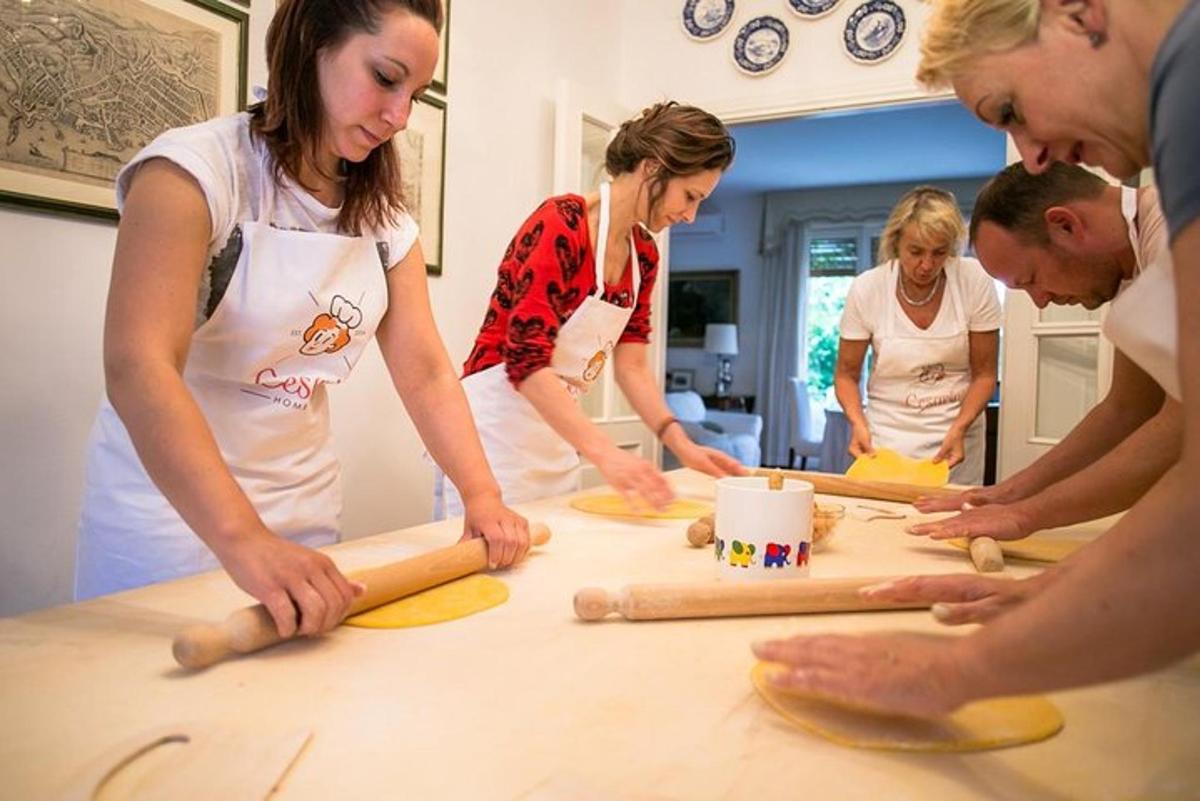 grupp inimesi, kes seisavad laua ümber ja teevad tainast
