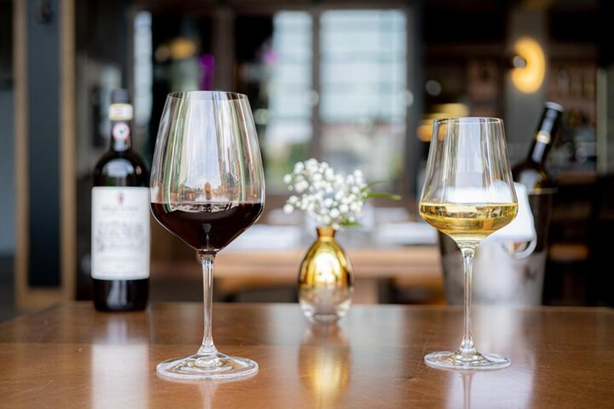 Dos copas de vino sobre una mesa con botellas de vino.