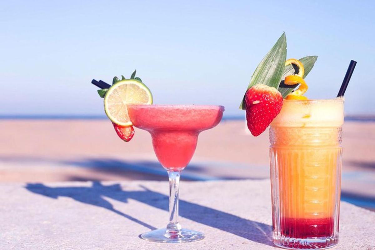 two cocktails sitting on a table near the beach