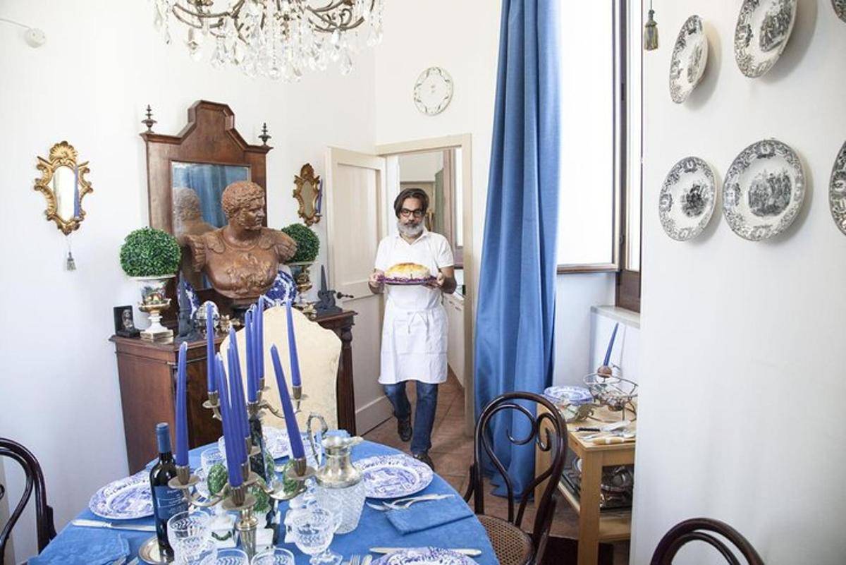 um homem segurando um bolo em uma sala com uma mesa