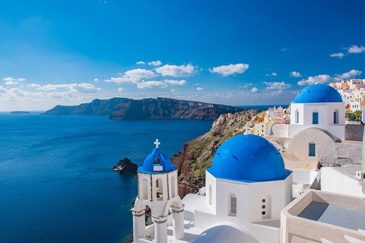 un gruppo di edifici bianchi con cupole blu e l'oceano