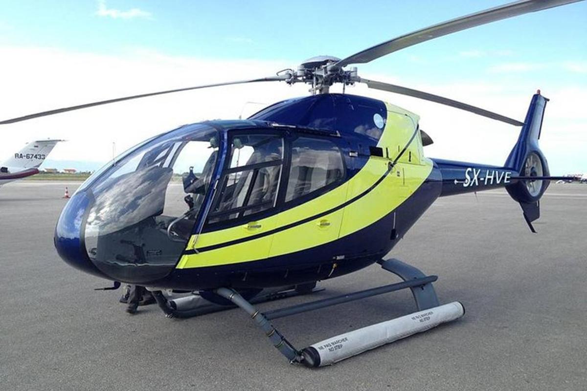 een blauw-gele helikopter geparkeerd op een landingsbaan
