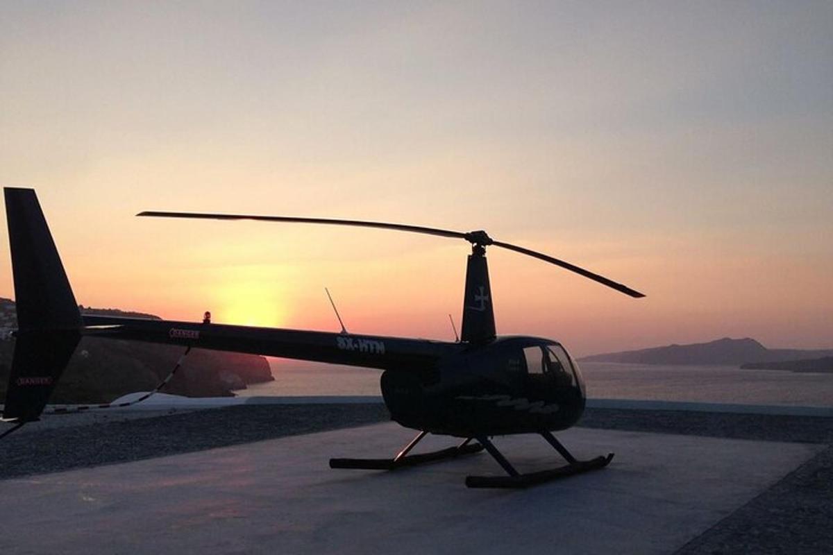 un hélicoptère stationné sur une piste avec le coucher de soleil en arrière-plan
