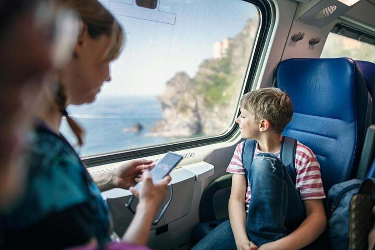 uma mulher e um menino sentados em um trem olhando para um celular