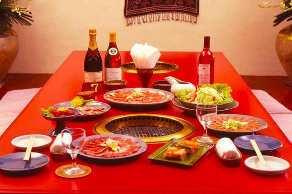 meja merah dengan piring makanan dan botol anggur