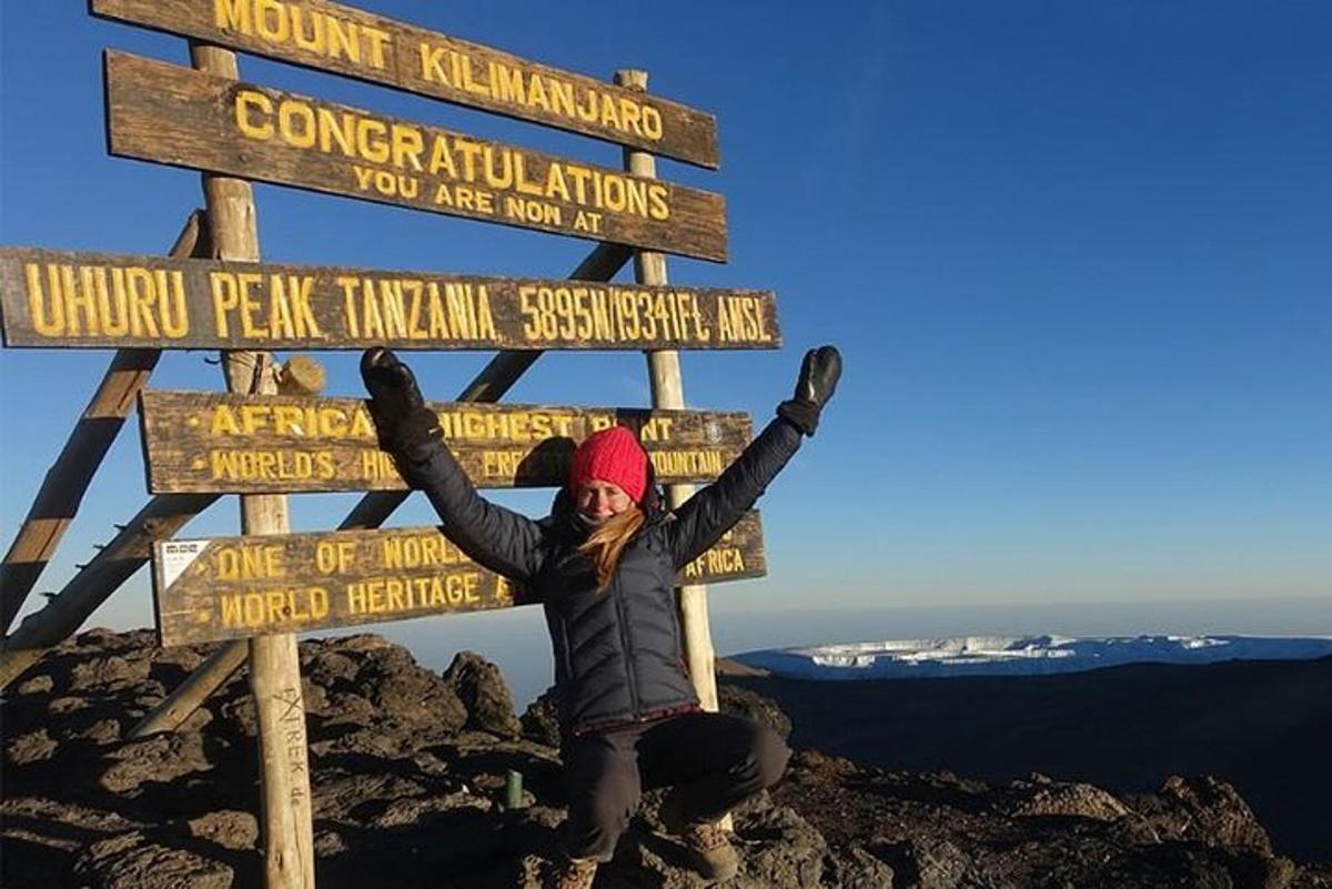 a woman standing next to a sign on a mountain