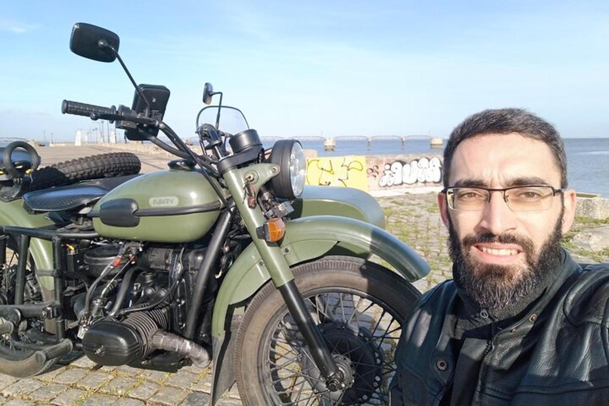 vīrietis ar brillēm stāv blakus zaļam motociklam