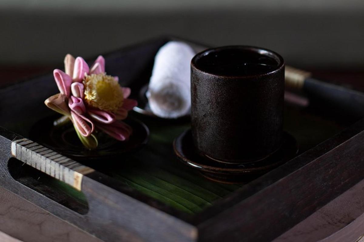 木製のトレイの上の黒いカップと花