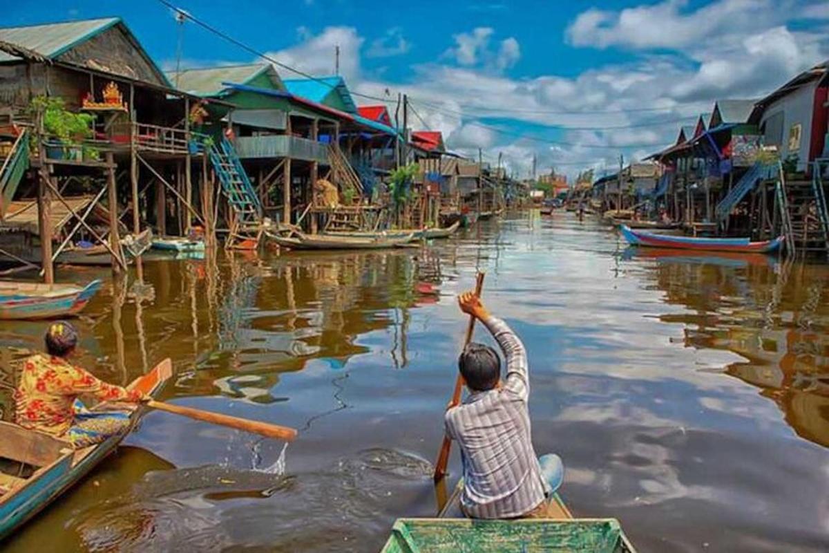 duas pessoas em barcos em um rio com casas