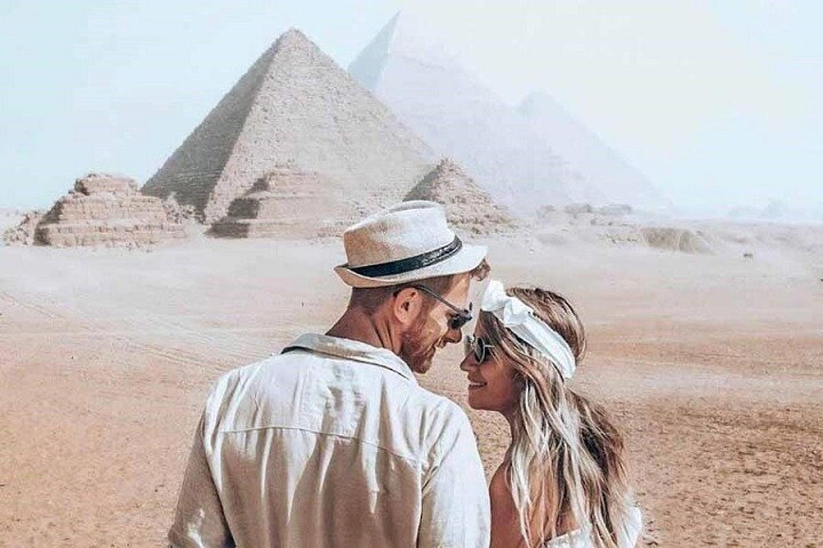 muž a žena stojící před pyramidami